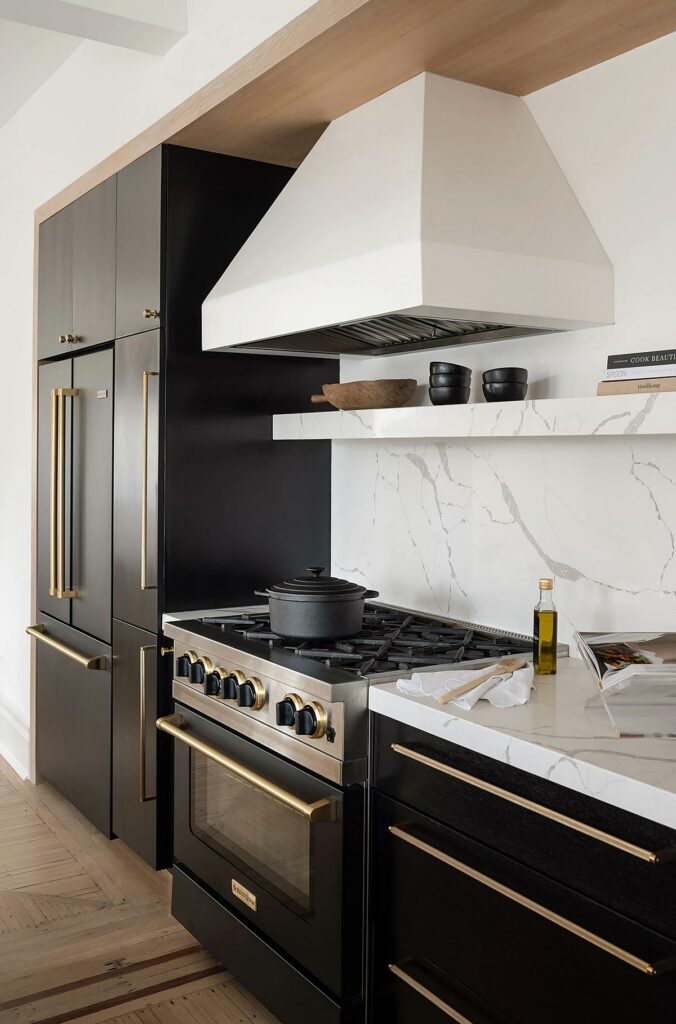 View of the kitchen with white marble tile, bronze fixtures, and black cabinets