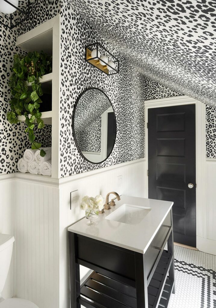 A small bathroom with detailed black and white leopard print on the upper walls and ceiling, wainscoting on the bottom