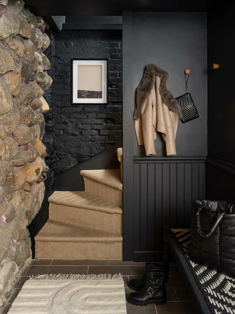 A curving stairway with a rubble stone wall on one side and black-painted stone on the other