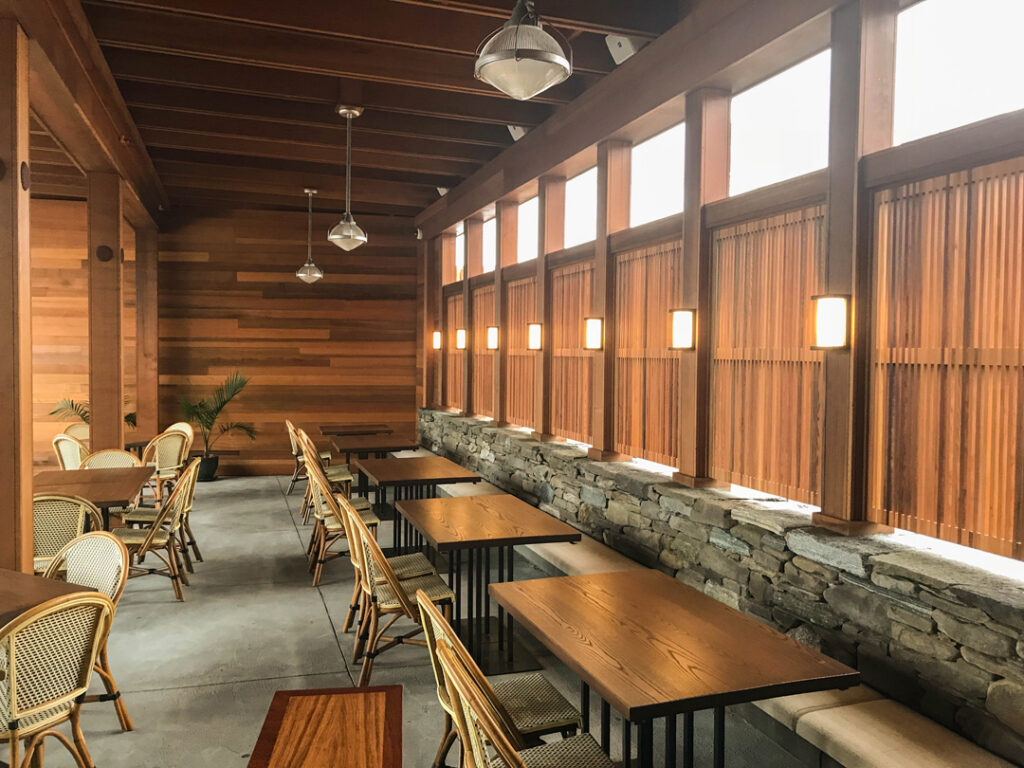 Dining seating area with stone work wall and vertical wooden slats over large windows