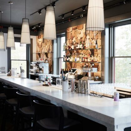 View of a white marble slab bar with decorative cutting board display on the back wall