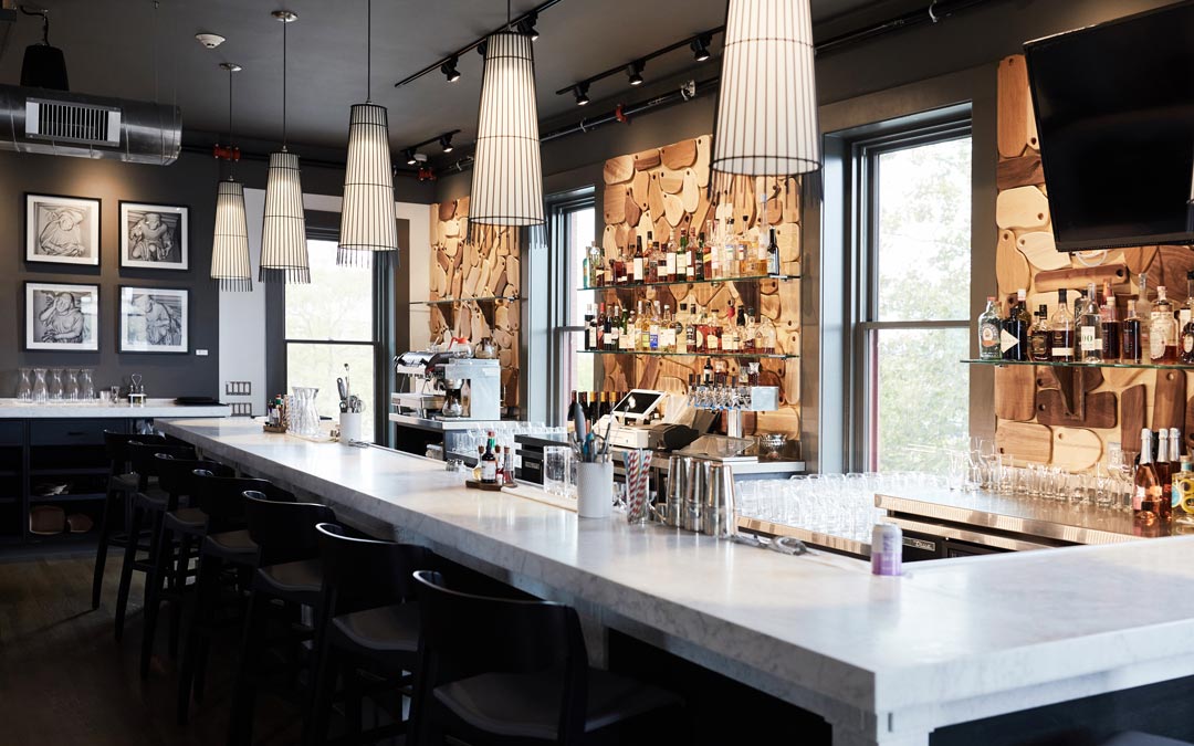 View of a white marble slab bar with decorative cutting board display on the back wall